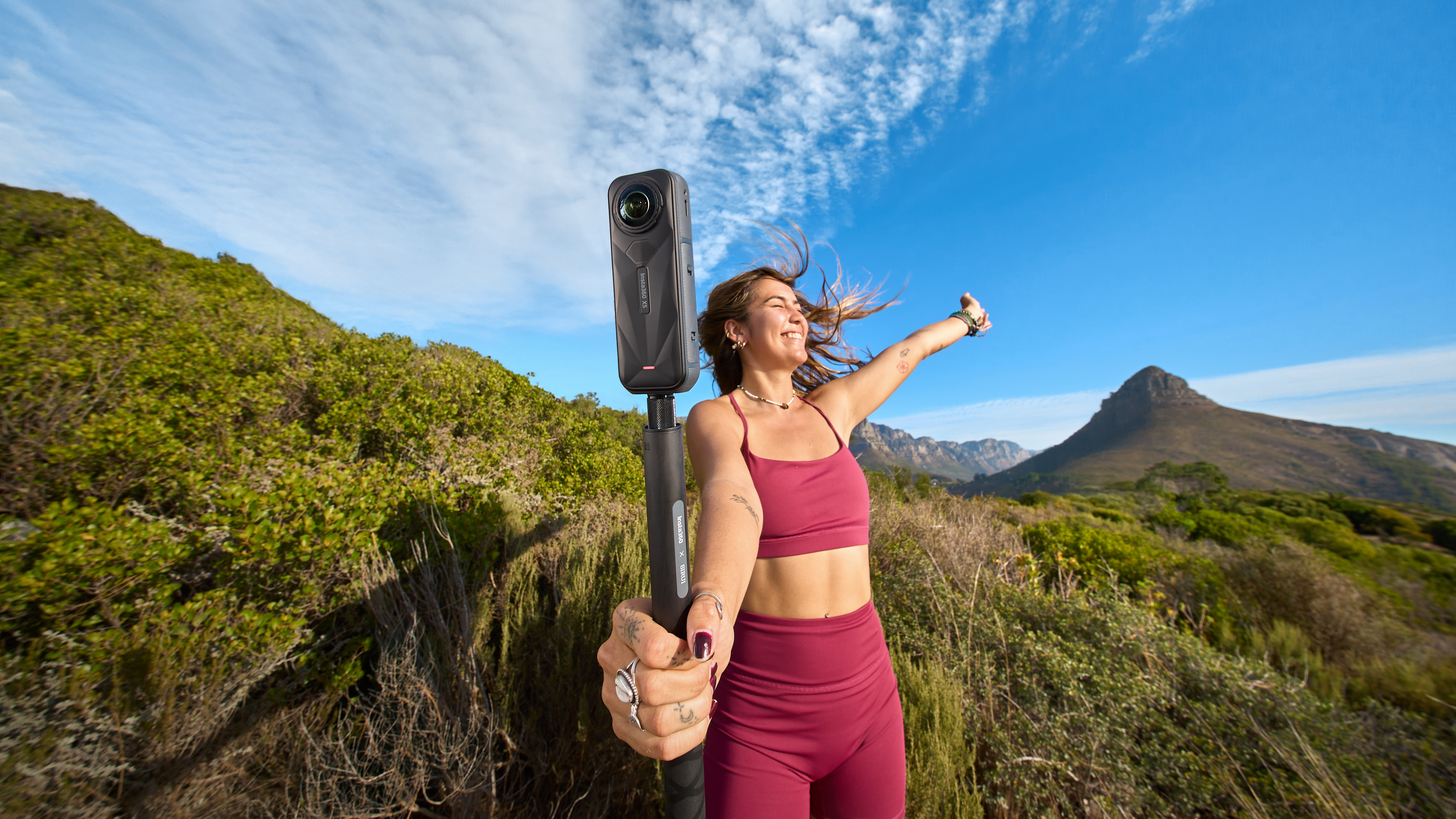 adventurer filming 360-degree hiking video with Insta360 X5 on mountain trail